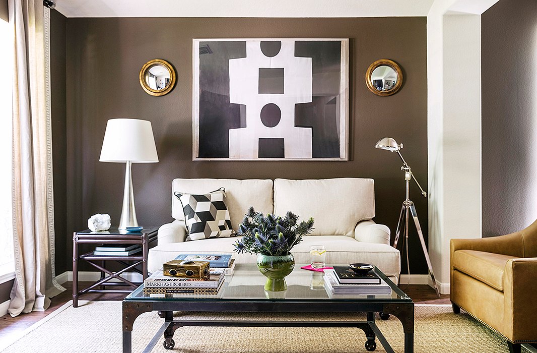 The home has two living rooms. Here, Paloma opted to create a cozy, chic salon vibe. The key? “Comfortable seating that lends itself to conversation,” she says. The English roll-arm sofa is custom. “I love how it pairs with the modern elements.” The coffee table and mirrors are vintage, and the artwork is by Paule Marrot.
