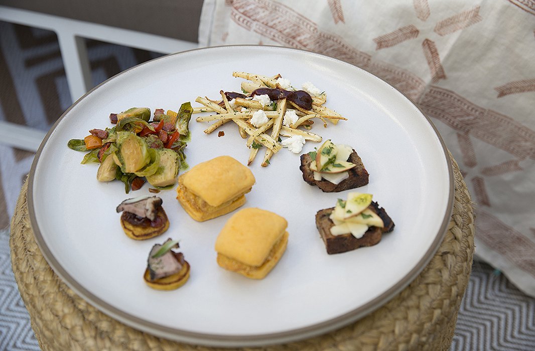 On a garden stool, an array of appetizers includes roasted brussels-sprout salad, parsnip pomme frites, and Pink Lady apple bruschetta.
