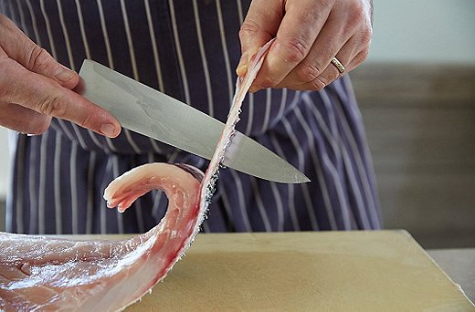 Once you’ve gotten a little ways in, flip the knife up and cut a vertical line, about two inches long, in the skin. That will give you something to grip as you cut off the rest of the skin.
