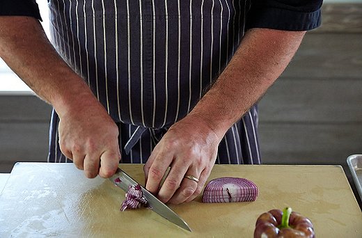 Turn each sliced onion piece flat down on board, and dice, moving the knife in a circle around the curve of the onion.
