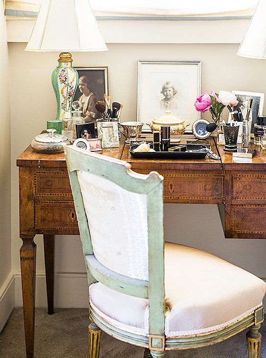 An antique vanity is dressed with family portraits and a pair of hand-painted table lamps.
