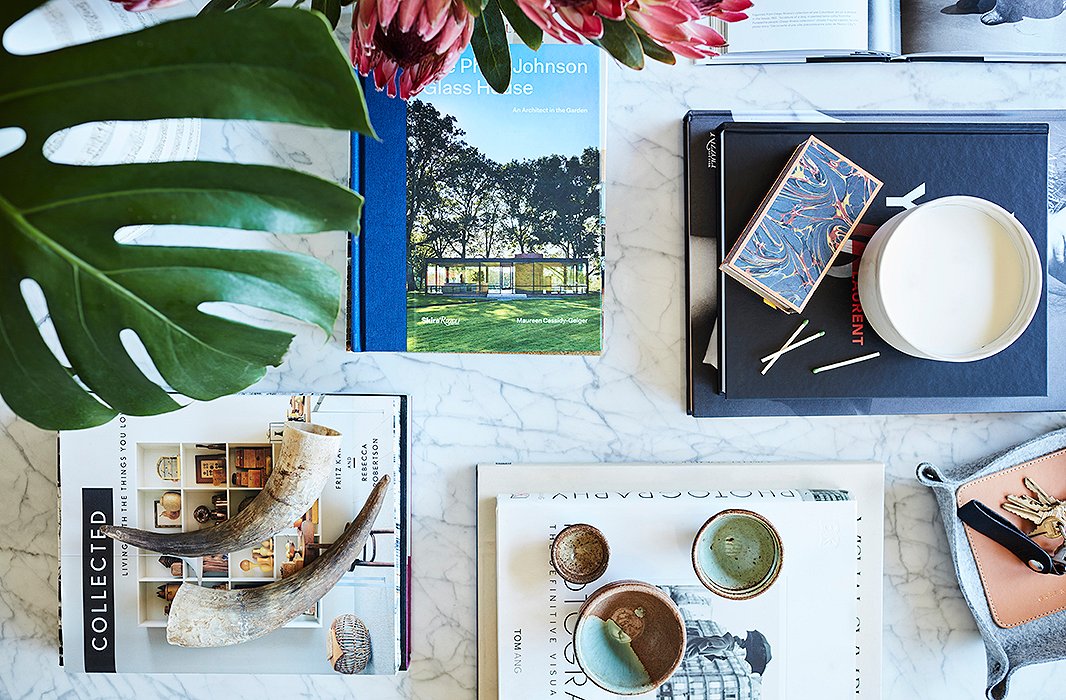 On the marble coffee table, a spread of fashion, design, and architecture influences. Alex says the oversize coffee table—it’s 48 inches square—was big enough to balance a grand-scale lighting fixture overhead, further focusing the eye on this central gathering spot.
