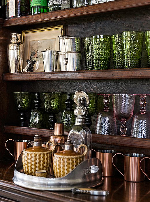 The bar displays colorful vintage glassware, copper mugs, and julep cups from family christenings.
