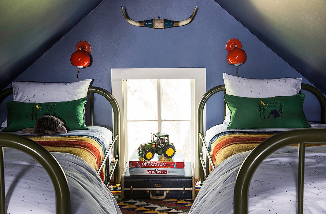 Constellation-print bedding by Biscuit Home, Pendleton blankets, and army-green Schoolhouse Electric beds in the loft let little guests feel as if they’re sleeping under the stars. “We kept it a dark blue like the night sky and wanted it to feel a like an old-timey boys’ camp,” Bailey says.
