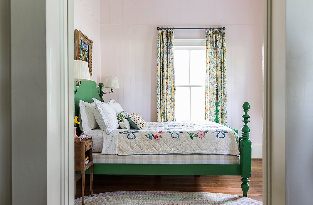 A vintage quilt adorned with ribbon and flower motifs pulls together the sweet palette of this farmhouse bedroom. Photo by Lesley Unruh.
