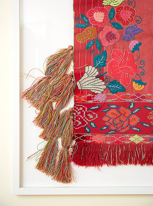 A Mexican textile floating (actually, sewn) on a mat to highlight its textured tassels and embroidery. Frame by Framebridge.  