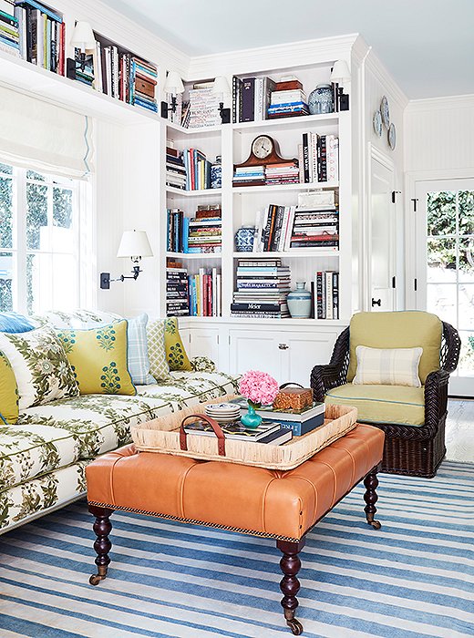 The cozy family room is a study in pattern and texture. “I love the mix of upholstery fabrics with the leather ottoman and wicker chairs,” says Mark. “The bookshelves balance the kitchen cabinets across the room.” The rug is antique, and the tray is Ralph Lauren Home.
