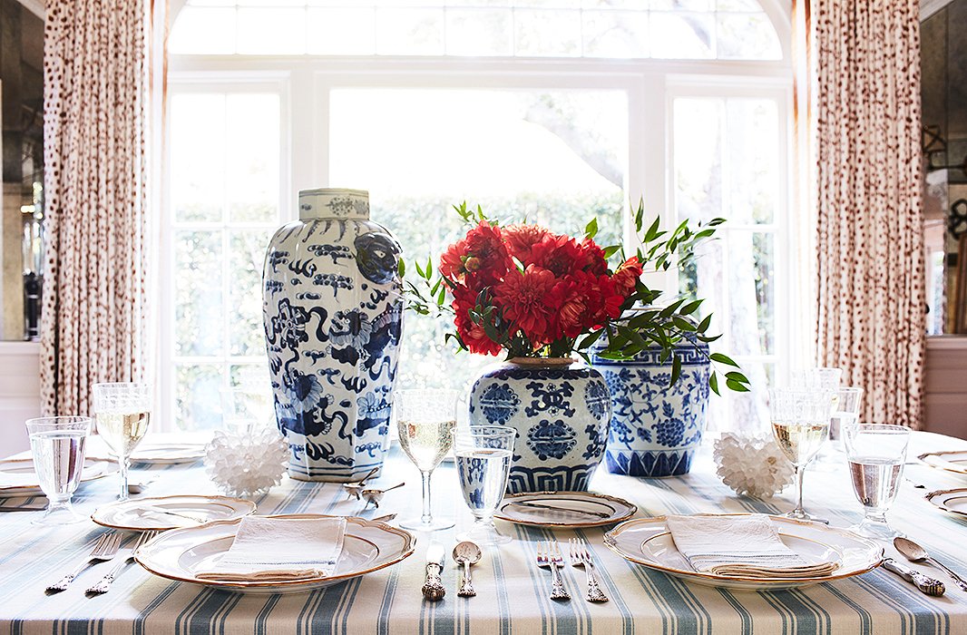 Put those ginger jars to work by turning them into centerpiece vases. We love the way they pair with gold-rimmed dinnerware and a simple striped tablecloth. Photo by Joe Schmelzer.
