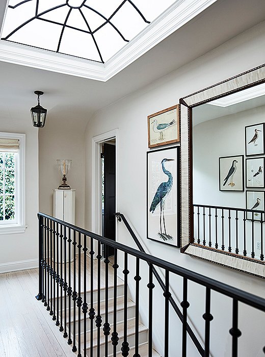 The skylight on the upstairs landing brings in lots of California light. “It adds drama and height to the space,” says Mark. Custom wrought-iron railings echo the window’s design. The bird prints are inspired by his friend Bunny Williams’s home in the Dominican Republic—“one of my favorite homes anywhere.”
