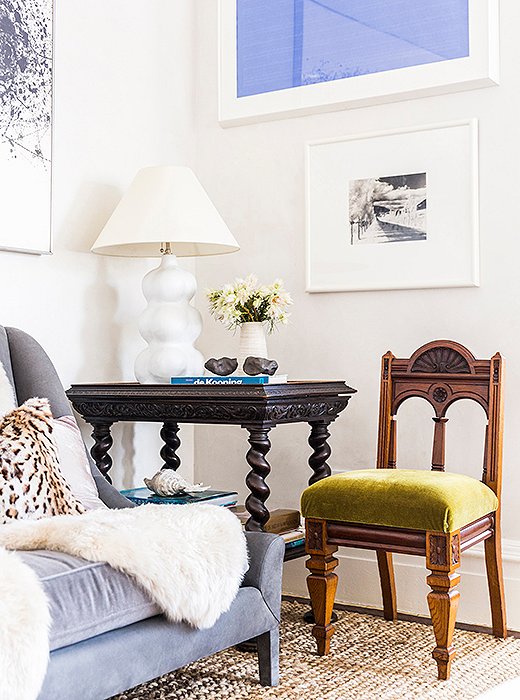 Touches of color—a dreamy blue painting, a green velvet chair—enliven the great room, which is grounded in neutral hues and layers of inviting texture.
