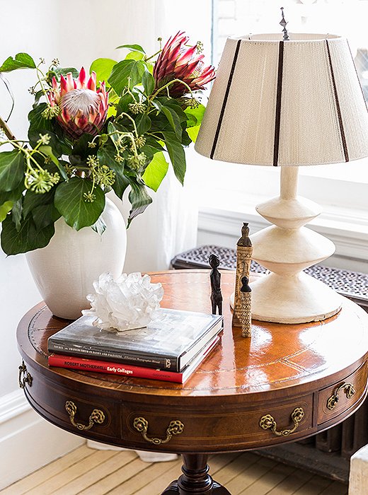 Throughout the home, unexpected pairings lend an eclectic, well-collected vibe. Case in point: an antique library table topped with a sculptural Giacometti-style lamp, alongside a crystal votive and African figurines picked up on husband Averill’s travels.
