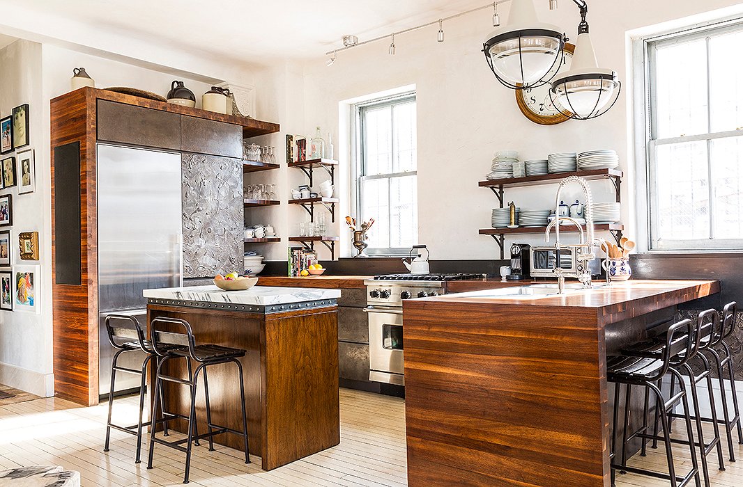 A big believer in wabi sabi, the Japanese concept of beauty in imperfection, Katie opted to leave the well-worn painted floor untouched. A plaster finish on the drawer fronts mimics the look of aged bronze, while industrial-style barstools provide extra seating. “There’s a really great flow,” Katie says. “We can accommodate a ton of people in that one large space… It’s very relaxed and easygoing, and we like it that way.”
