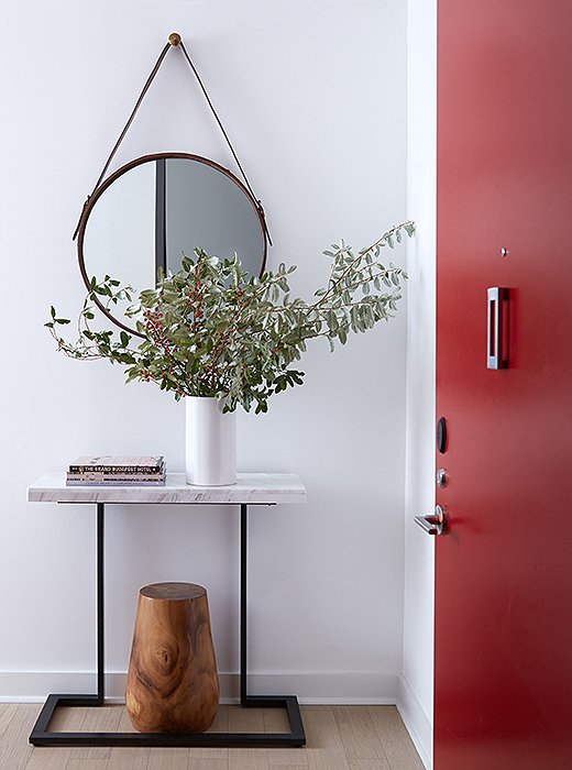 A console by the townhouse’s interior entrance provides a convenient spot to drop keys or mail. “That was all about the geometric play,” says David. “I softened the rectangular console table with the circular mirror and then added some weight to the table with the wooden stool underneath.”
