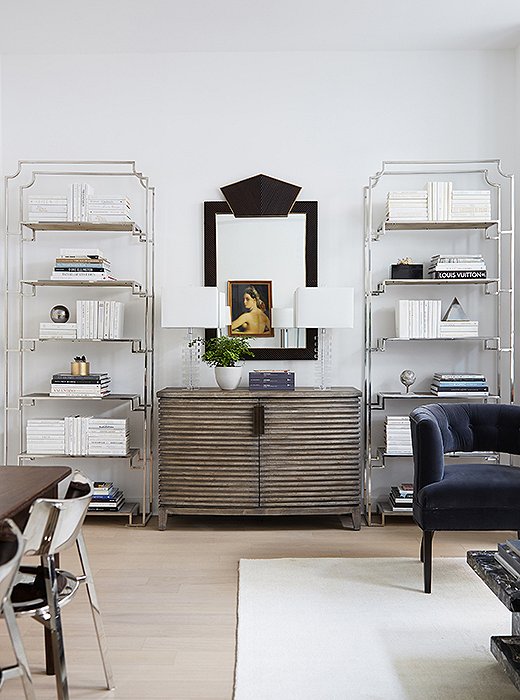 The townhouse has 11-foot ceilings, so David chose tall étagères to play up the soaring space: “I was looking for something more skeletal, so they didn’t detract from the clean lines of the space.” He placed them on either side of a chest and completed the vignette with an Art Deco–style mirror and crystal lamps.
