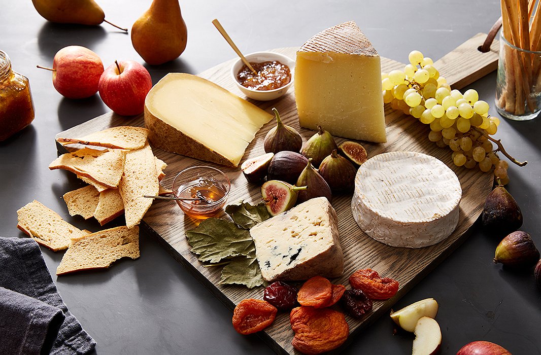 A wood board adds to the organic beauty of this delicious display of cheeses and seasonal fruits.
