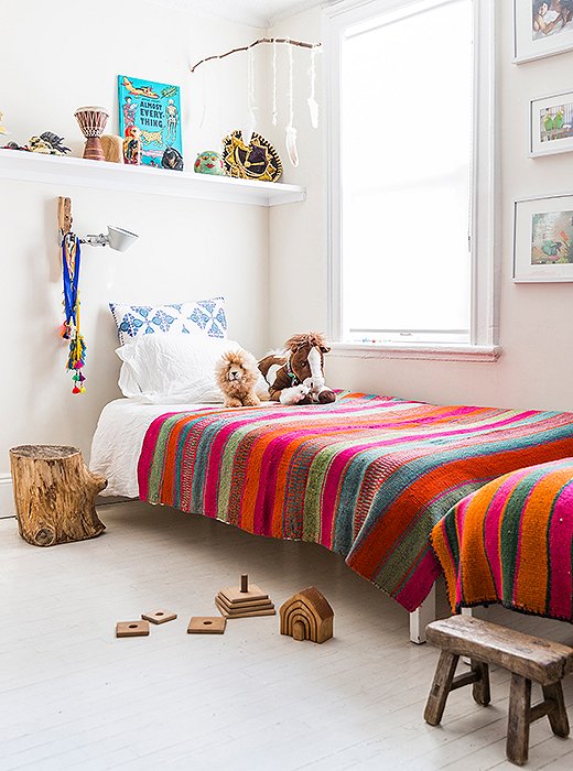 Twin beds line a wall in Son and Harmony’s room. “That was the best way to fit them in the space,” she says. “I’m not into bunk beds, and I feel that it promotes brotherly bonding.” She also installed shelves above each bed for toys and books. “They do their own curating on their bookshelf.”
