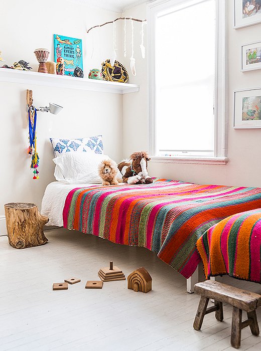 Twin beds line a wall in Son and Harmony’s room. “That was the best way to fit them in the space,” she says. “I’m not into bunk beds, and I feel that it promotes brotherly bonding.” She also installed shelves above each bed for toys and books. “They do their own curating on their bookshelf.” 