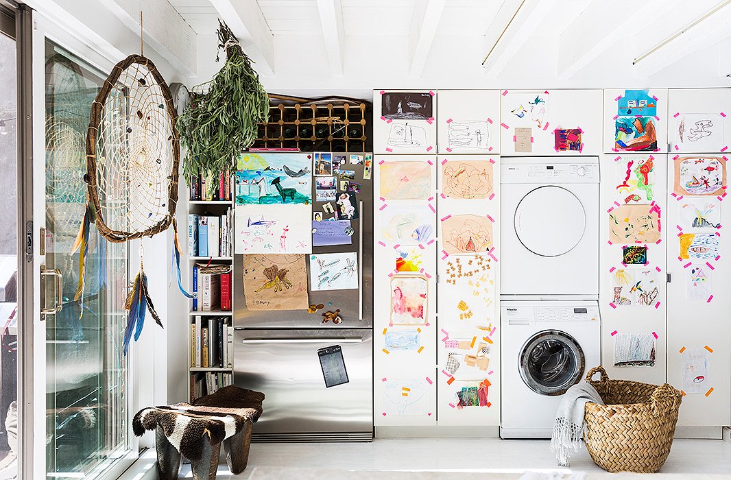 Jenni used colored tape to turn a wall of cabinets into a gallery for her children’s artwork. “It’s always changing,” she says. “We take stuff down and put new stuff up.” A large dreamcatcher from Peru hangs beside a bundle of sage, from Jenni’s farm upstate, which was turned into sage sticks at Son’s birthday party. 