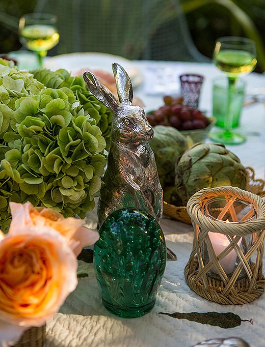Soft candlelight gives everything a glow—including green glass globes that once graced Rebecca’s parents’ dining table in the Bahamas. The silver rabbits were a gift from her godfather.
