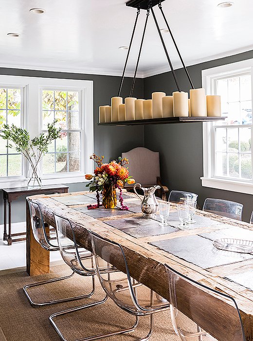 Daniel designed the dining room table out of reclaimed barn beams and slate tile. “That table is not moving,” laughs Alicia. “It had to be built in there.” For dinner parties, Alicia uses chalk to write the names of guests on the slate in lieu of place cards. They paired the rustic table with modern plexiglass chairs to bring balance to the space.
