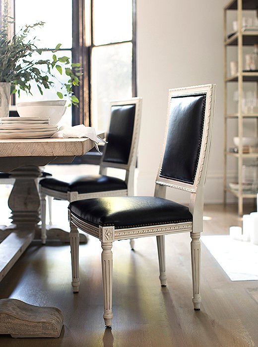 Black leather gives traditional Louis XVI-style chairs a glamorous update, while a weathered wood table brings the formality down a notch.
