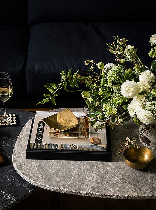 Marble coffee tables and brass accents make the space feel like a curated home.
