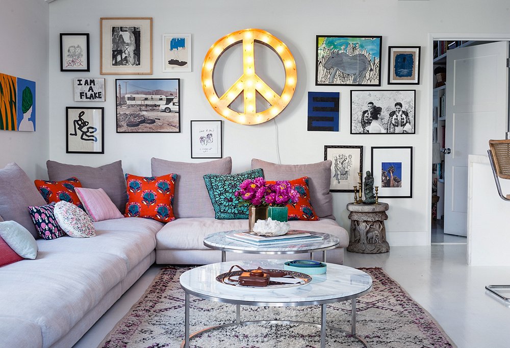 A peace sign, found at Nickey Kehoe, lights up the living room day and night. On arranging art, Irene says, “I really just throw art up on the walls. I build out from the center as I collect and just add new pieces.”
