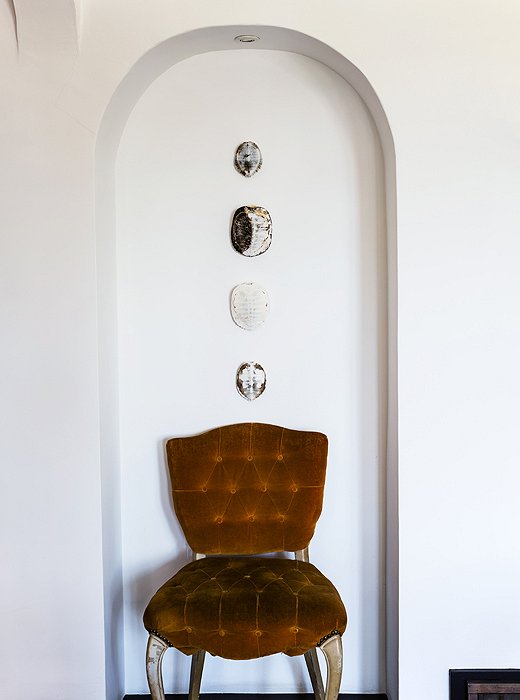 Making the most of every nook, Lizzie displays turtle shells and a vintage button-tufted chair in a small alcove.
