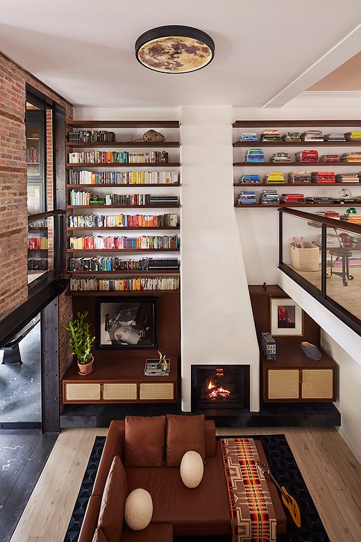 The multistory bookcase is the main feature of the living area. “I must’ve redesigned the bookcase 50 times,” says Olivia. Dotted amongst the books are pieces of art and a hornet’s nest, a gift from Olivia’s friends at Brook Landscape. The moon ceiling fixture is from friends and artists Ben and Aja Blanc.
