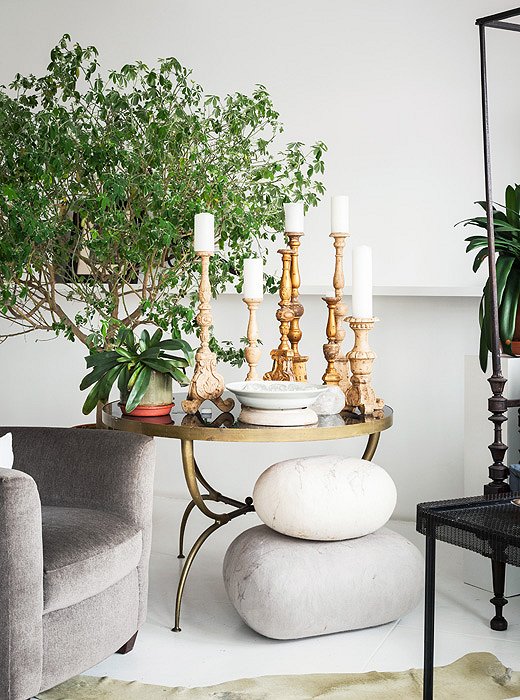 The warm tones of 19th-century candlesticks on a 1960s table provide a contrast to the verdant backdrop: a tree that Vicente “grew from a seed” some time ago.
