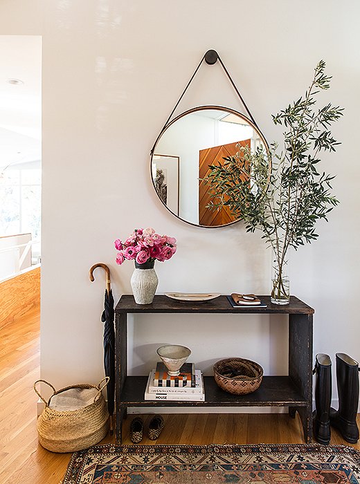 The entry illustrates the couple’s ethos of “less is more.” A console from Galerie Half holds pottery from Californian and Japanese ceramists. (David Korty and Akio Nukaga are favorites.) The front door, designed by Jed, is seen in the BDDW mirror’s reflection. 