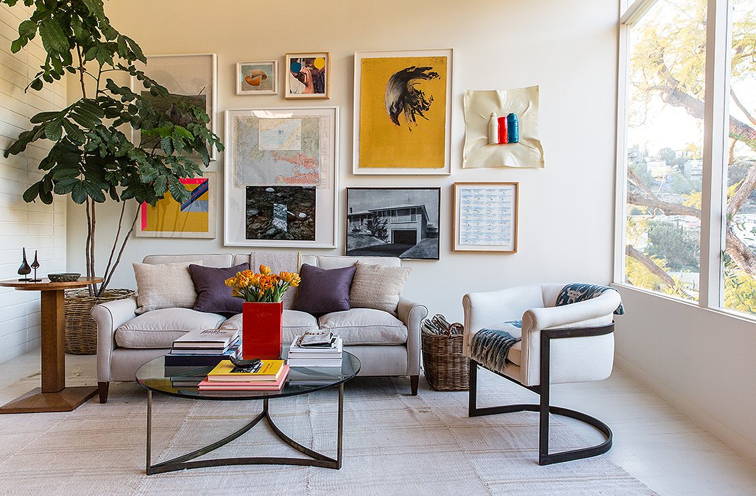 Jed’s parents and the couple are passionate art collectors, resulting in a bold gallery wall. The piece “hiding behind the tree is one of Jed’s,” says Jessica. The furniture is a mix of “custom, vintage, flea market, and inherited pieces, like a Milo Baughman chair.”
