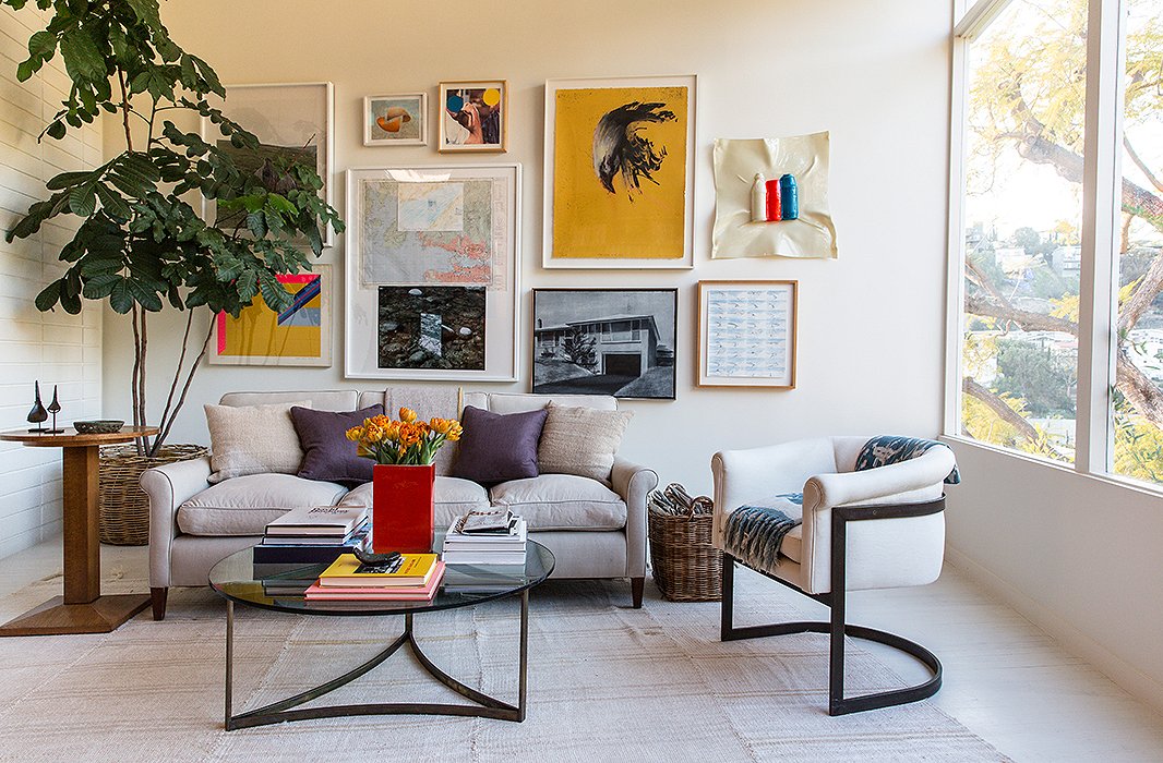 Jed’s parents and the couple are passionate art collectors, resulting in a bold gallery wall. The piece “hiding behind the tree is one of Jed’s,” says Jessica. The furniture is a mix of “custom, vintage, flea market, and inherited pieces, like a Milo Baughman chair.” 