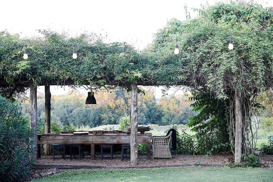 A rustic pergola covered in overgrown vines is one of the property’s many outdoor dining and lounge areas.

