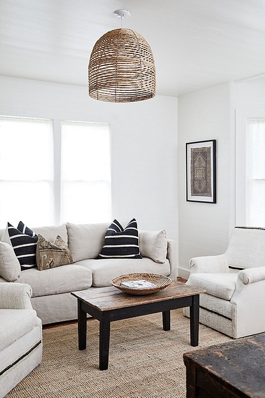 Pillows covered in Moroccan Berber wool and an Anatolian kilim top a linen sofa in the Farmhouse, the oldest building on the property. A coordinating framed global textile adorns the wall. 
