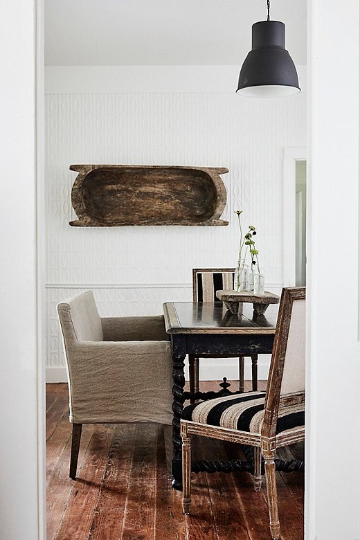 A barley-twist table and side chairs upholstered in a textural stripe provide unexpected details in the Farmhouse and play well off the building’s original pine flooring. 
