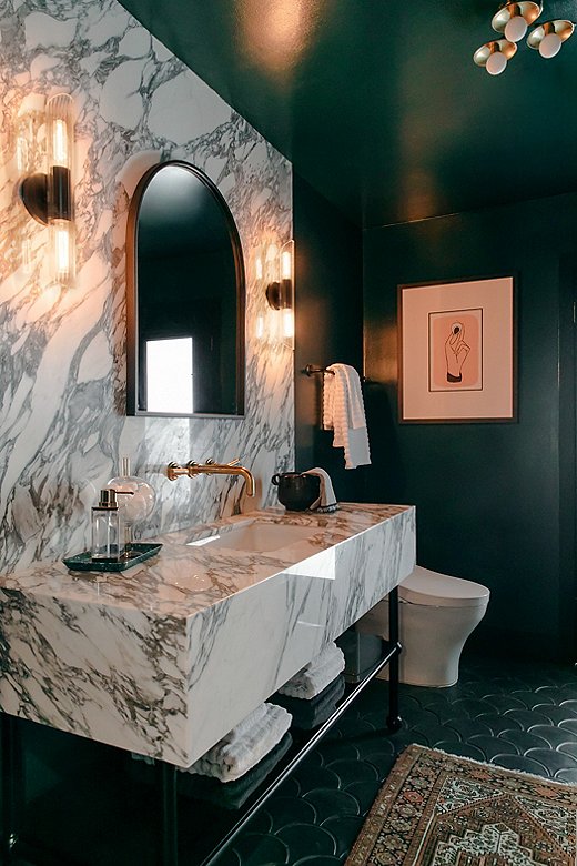 Jessie went moody in the main bathroom, painting the space Night Watch by Benjamin Moore. Black-and-white marble steals the show, while the sconces and the arched mirror add a touch of Deco glam.
