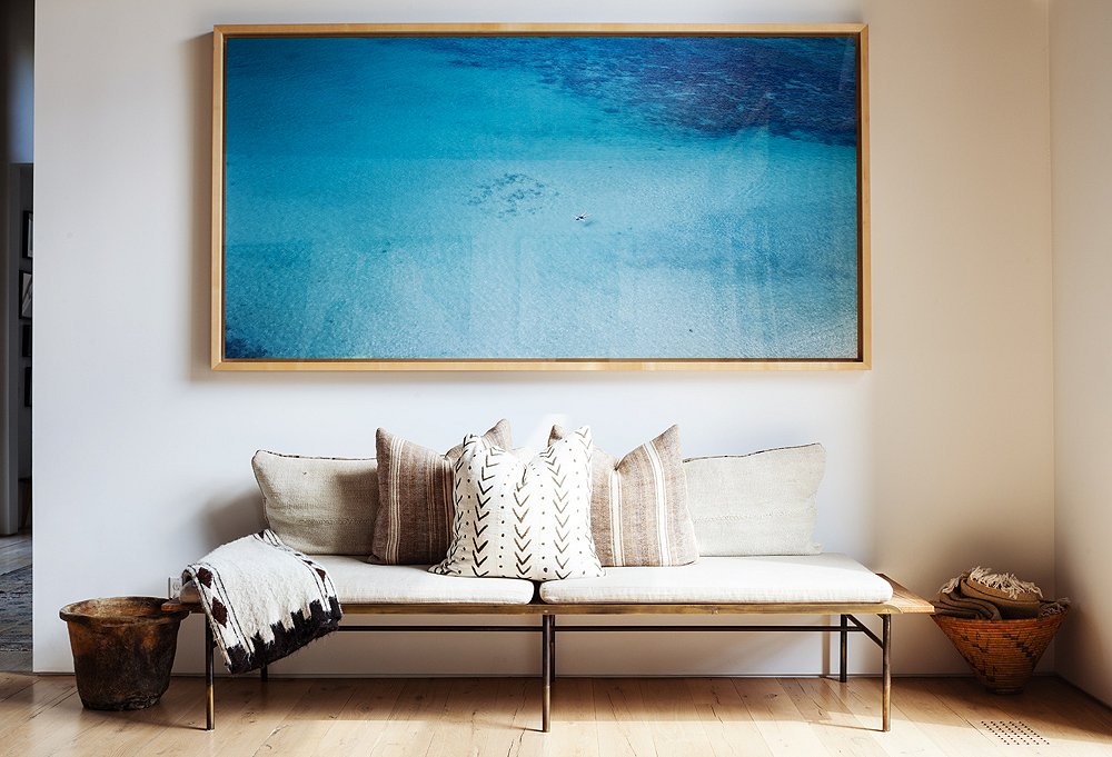 A Richard Misrach photograph was the perfect solution for a blank living room wall. The welcome burst of color fits in thanks to the neutral vintage textiles below—some are rugs turned into pillows.

