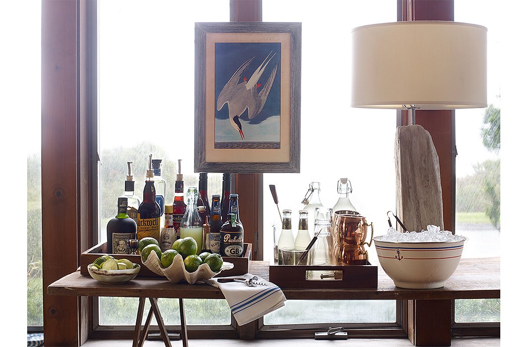 The sunroom console was transformed into a bar for the occasion. Trays corral liquor and drinkware, making cleanup as easy as pie. (Style tip: Place limes and other garnishes in a jumbo clamshell to keep things in theme, and make your own ice bucket with an oversize bowl and a pair of tongs.)
