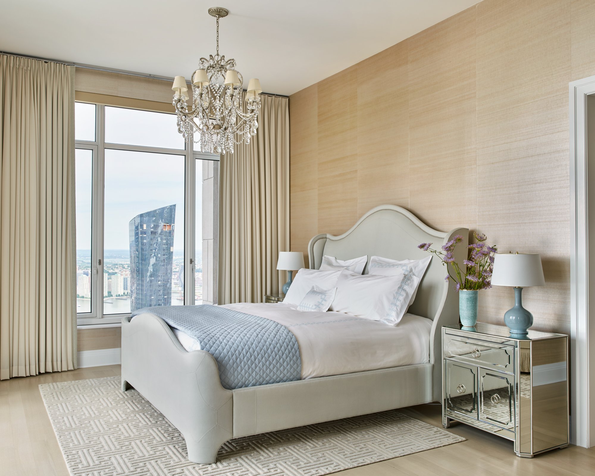 The master bedroom is a study in relaxed elegance. The showstopping Ralph Lauren Home chandelier takes center stage. The Matouk bedding adds subtle color, as do a pair of sky blue lamps.
