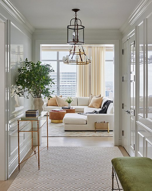 The entryway sets the tone for the rest of the apartment. “I really love the entryway and the living room and how they speak to each other,” says Ariel. “From the green velvet on the bench to the navy lacquer on the bar, the rich camel leather and the beige hide rug, it all speaks to each other in a really fun way.”
