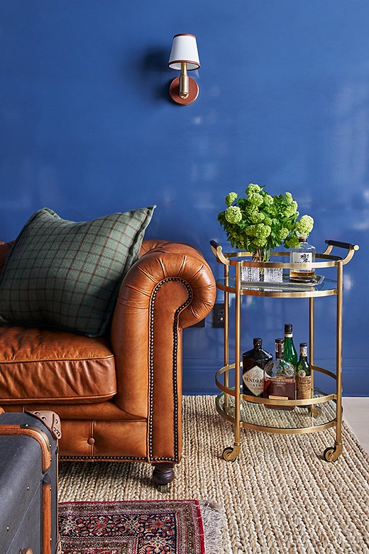 The study, which Ariel describes as a “cozy man cave,” is layered with masculine elements like these leather-wrapped sconces from Ralph Lauren Home. The room is lacquered in a blue hue from Fine Paints of Europe mixed by NYC Fine Finishes, which also lacquered the entryway and dining room. “If you’re looking for some wow factor, lacquer is definitely the way to go,” Ariel says.  
