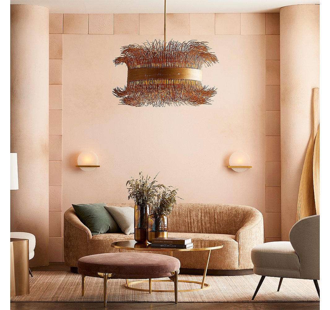 With its barely tamed rattan fringe (cinched with steel in a gold finish), the Filamento chandelier by Laura Kirar provides an organic counterpoint to the sleek and sophisticated Savion sconces made of onyx and steel. Likewise, the slender straight and splayed legs of the ottoman and the chair contrast with the curves dominating the room.
