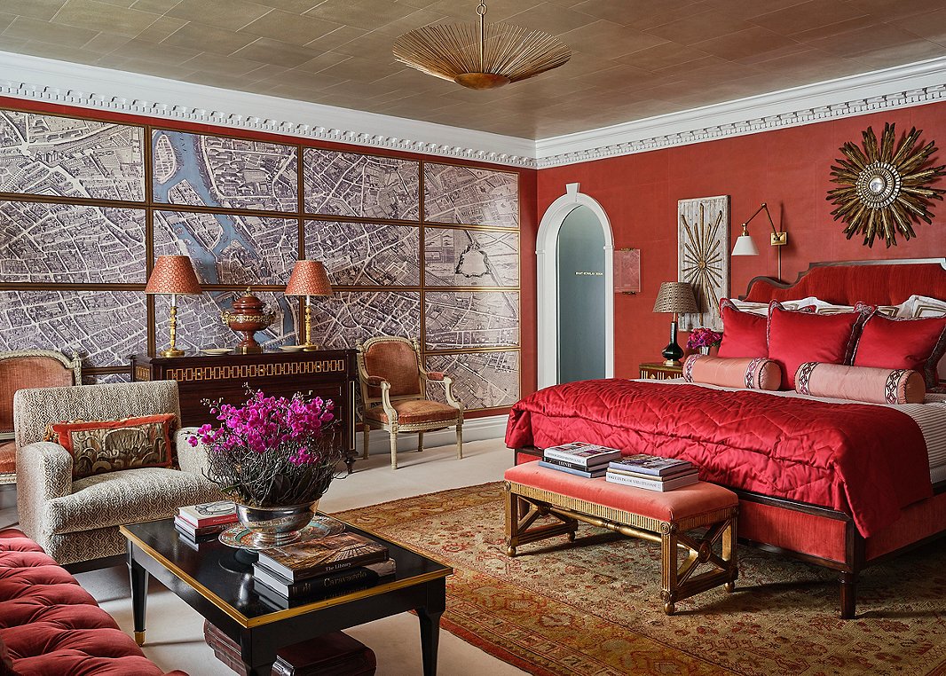 “Everyone says you can’t do a red bedroom, and the contrarian that I am wanted to do it,” laughs Alexa Hampton. The seemingly multipart wall map of Paris is actually a trompe l’oeil work from a new collaboration between Alexa Hampton for Mark Hampton LLC and Gracie Studio. To further offset the red, Alexa added bright white molding and taupe ticking-stripe bedding from Eastern Accents. “It’s a nice pu pu platter of a room,” Alexa says. Photo by Stephen Karlisch. 
