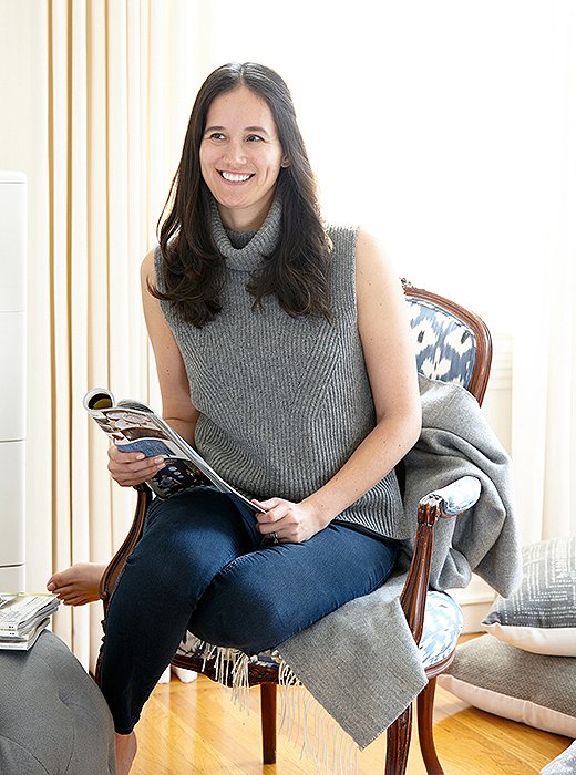 Caitlin perches in the rare exception to her gray, white, and neutral palette, a blue ikat-upholstered chair.
