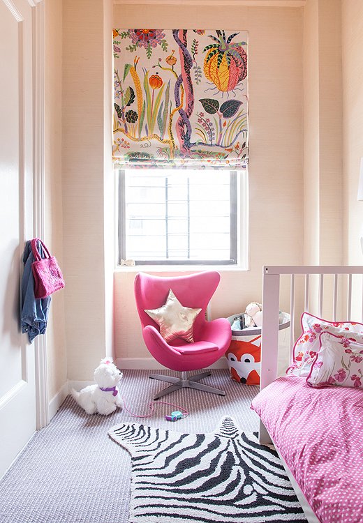 A Roman shade crafted from Josef Frank fabric hangs over a sleek, baby-size egg chair in youngest daughter Daisy’s room.
