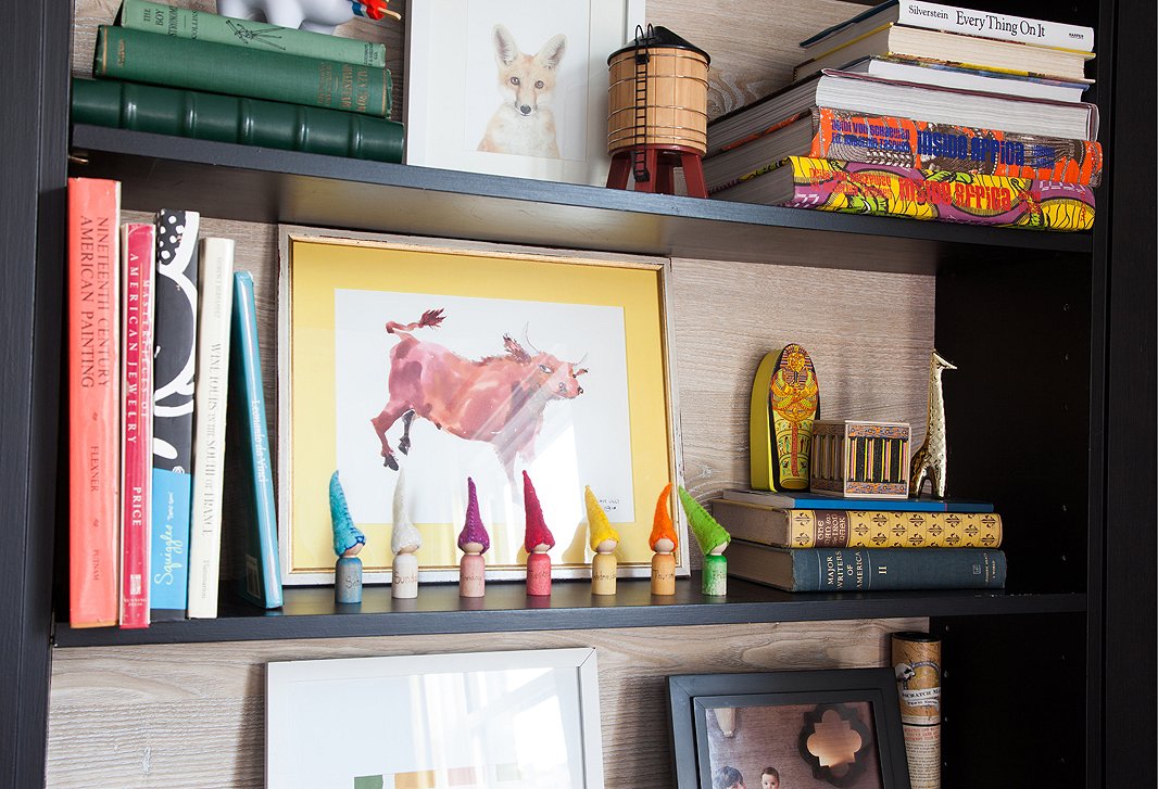 Favorite books, curios, and pieces of art, including a baby fox print from The Animal Print Shop, share space on Lilly’s dining-room bookcase.
