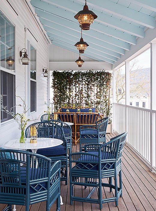 The restaurant seats lunch and dinner guests on the covered side porch. The bamboo furniture gets a modern makeover in bright blue, one of the hero colors throughout the property.
