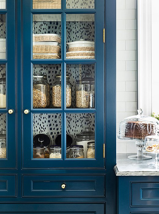 Les Touches appears again at the back of a kitchen cabinet reserved for dry goods and casual serveware—a simple trick that provides continuity between the two rooms. 
