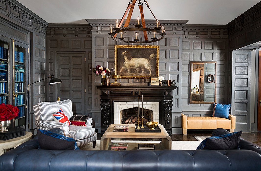 A prancing spaniel presides over the original Tudor-style mantel, given a fresh look with a brass trophy and stacks of vintage books. Beneath a rectangular mirror, a  leather bench by Brownstone Upholstery makes for a cozy fireside perch.
